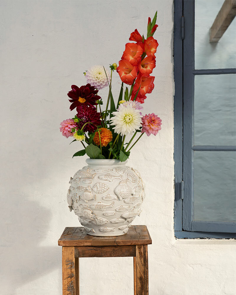 Madam Stoltz, collection été 2026 : Bouquet de fleurs, dans un vase en terre cuite Madam Stoltz, collection été 2026 : Bouquet de fleurs, dans un vase en terre cuite, avec des motifs sculptés de poissons