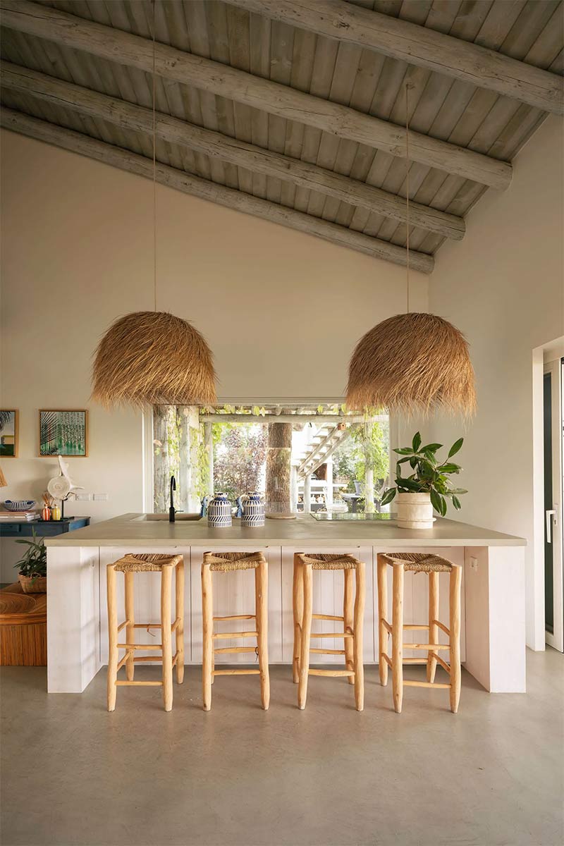 La cuisine ouverte sur le séjour, avec un îlot central en béton et une déco ethnique chic
