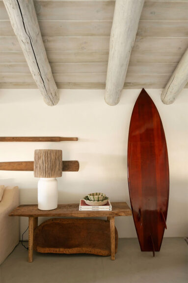 Détail d'une des chambres, avec déco planche de surf et luminaire en raphia