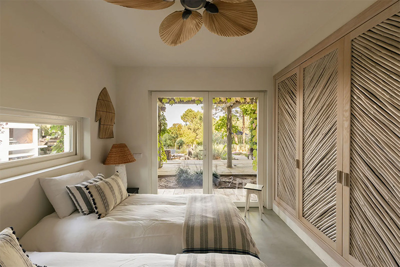 Une chambre à deux lits dans un style ethnique chic avec de grands placars aux portes en cannage
