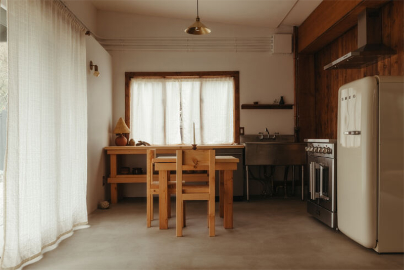 La cabane Coveside Carriage House - L'espace repas avec sol en béton ciré et meubles en bois