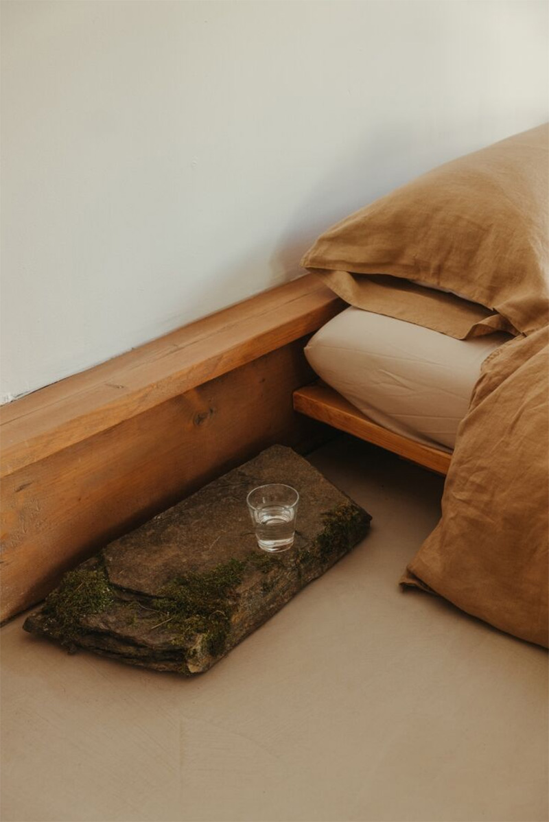 La cabane Coveside Carriage House - Le lit bas en bois et sa table de chevet en pierre, très japandi