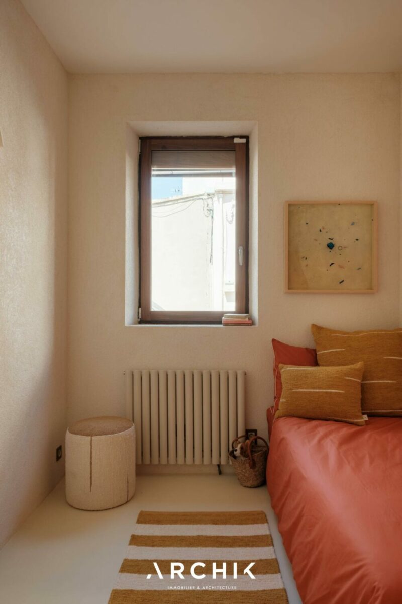 La chambre d'enfant monochrome crème avec un couvre lit terracotta La chambre d'enfant monochrome crème avec un couvre lit terracotta