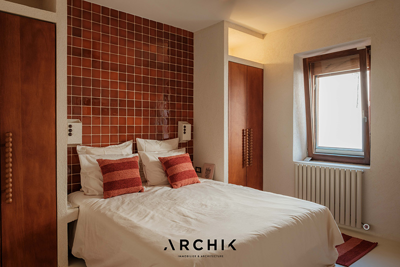 La chambre parentale avec une tête de lit en carrelage terracotta encadré de deux armoires La chambre parentale avec une tête de lit en carrelage terracotta encadré de deux armoires