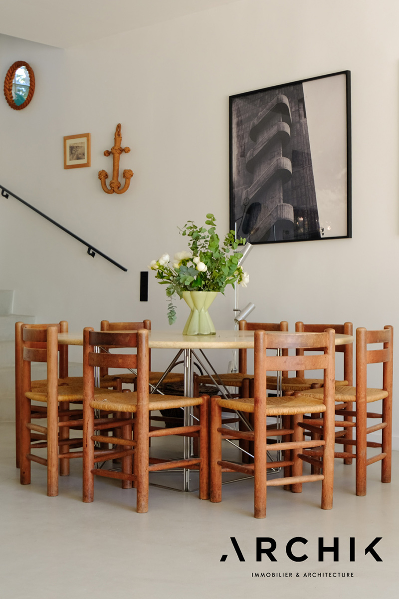 La grande table ronde de salle à manger et sa collection de chaises en paille vintage La grande table ronde de salle à manger et sa collection de chaises en paille vintage