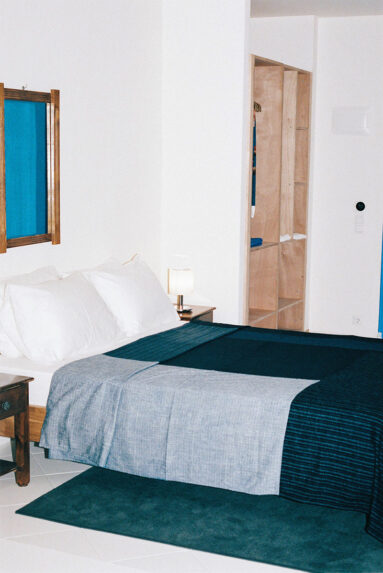 Une chambre minimaliste toute blanche, rehaussée de textiles marine
