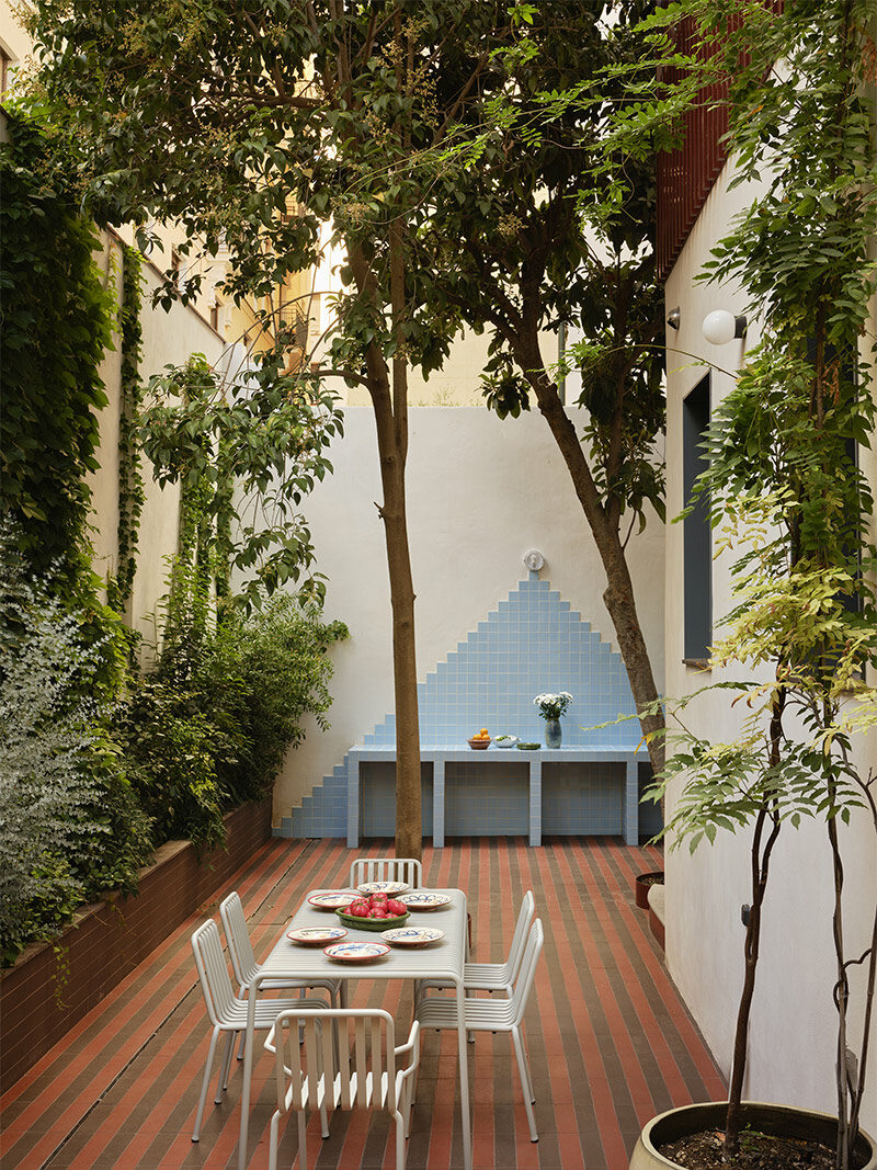 Coin repas, aménagé avec du mobilier Hay et au fond, l'espace cuisine extérieure avec son jeu de carrelage en pyramide bleu pastel Coin repas, aménagé avec du mobilier Hay et au fond, l'espace cuisine extérieure avec son jeu de carrelage en pyramide bleu pastel