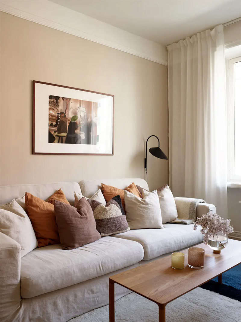 Canapé beige moderne agrémenté d'une accumulation de nombreux coussins moelleux aux textures variées