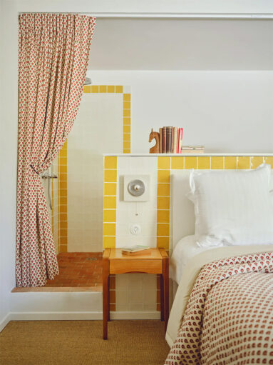 Une des chambres avec la tête de lit avec le coin douche placée derrière la tête de lit Une des chambres avec la tête de lit avec le coin douche placée derrière la tête de lit, décoré avec une frise de carreaux 10x10 jaunes