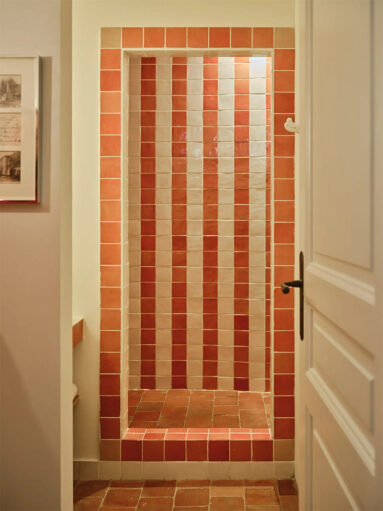 Une douche décorée avec des rayures formées par des carreaux de terracotta et crème Une douche décorée avec des rayures formées par des carreaux de terracotta et crème